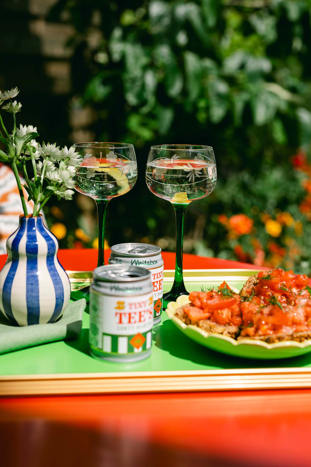 Vintage hock wine glasses on a garden table with tomato salad and striped vase