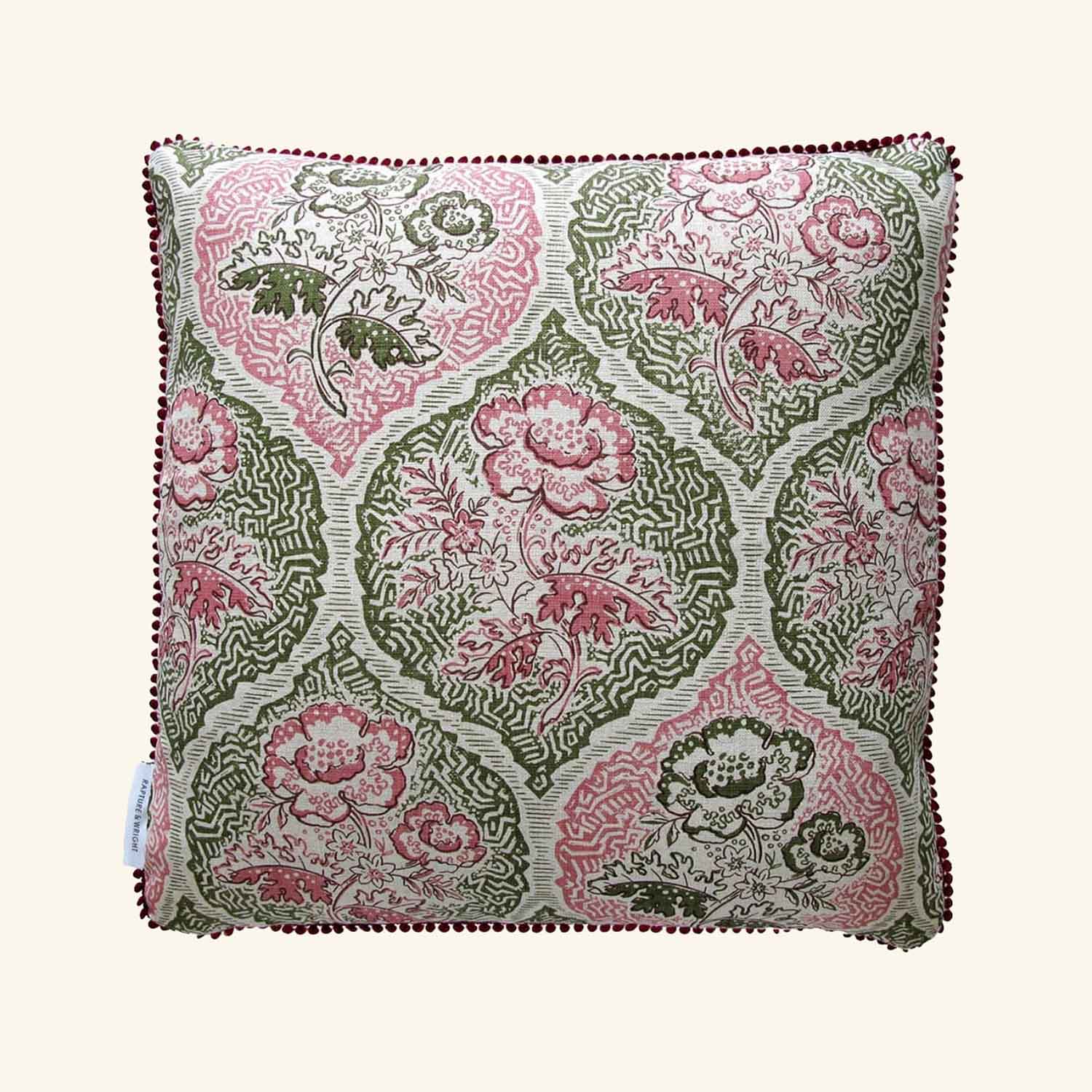 A square-shaped linen cushion with a floral pattern in pink and green colors, featuring bobble piping along the edges.
