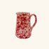 Red and white speckled ceramic pitcher on a white background