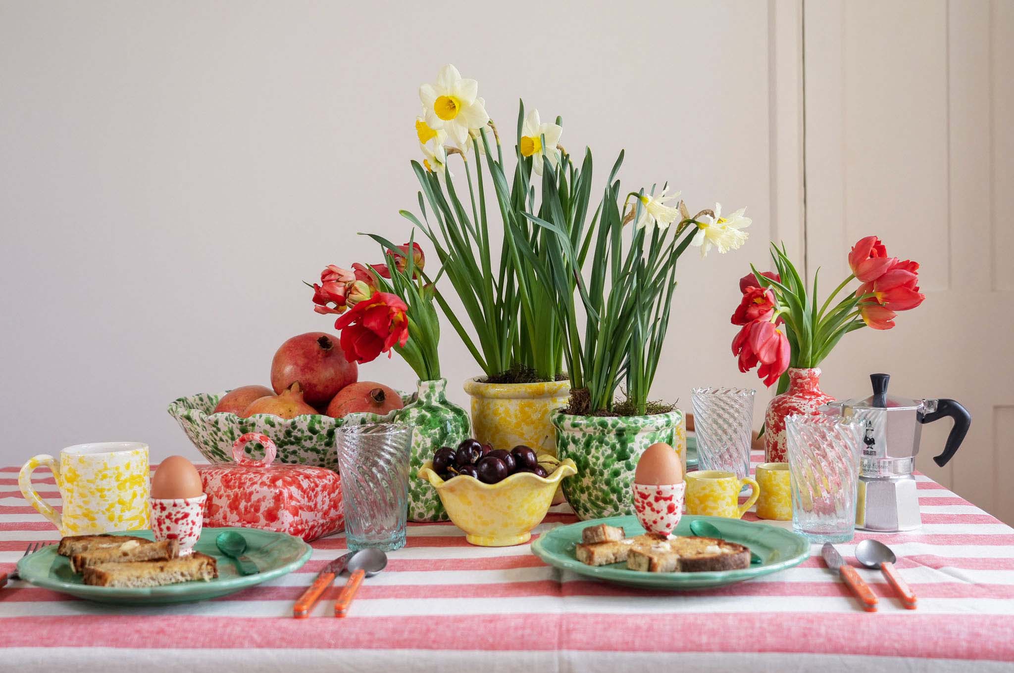 Table setting with flowers, food, and tableware on a striped tablecloth. LAMP LDN LIVING