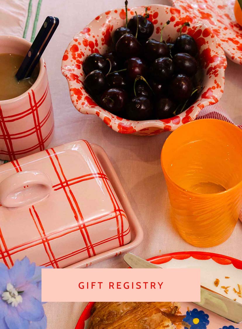 Table setting with a bowl of cherries, cups, and a container with 'Gift Registry' text overlay. LAMP LDN LIVING