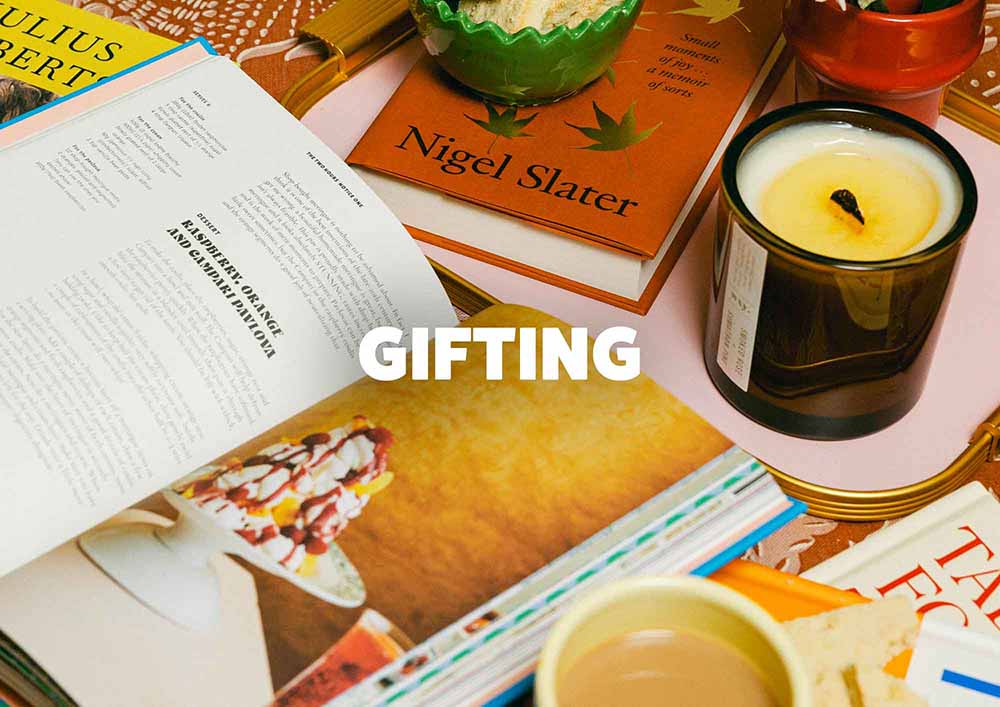 Open book with a candle and other items on a table, with 'Gifting' text overlay. LAMP LDN LIVING